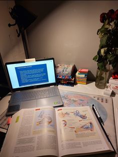 an open book sitting on top of a desk next to a laptop computer and books