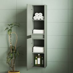 a bathroom with green walls and white towels on the shelf next to a potted plant