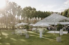 an outdoor wedding venue with white tables and umbrellas