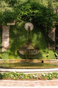 an outdoor fountain surrounded by greenery and trees