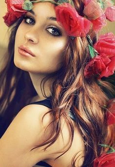 a woman with green hair and red flowers in her hair is posing for the camera