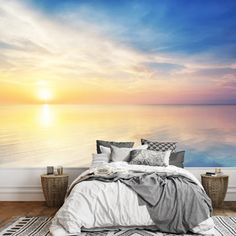 the sun is setting over the ocean wall mural in a bedroom with a bed and rug