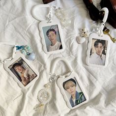 four keychains with pictures of people hanging from them on a white cloth covered bed