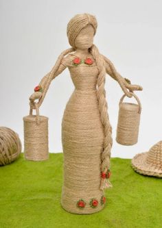 a woman holding two buckets on top of a green rug next to straw hats