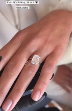 a close up of a person's hand with a diamond ring on their finger