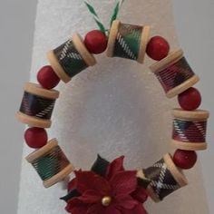 a christmas wreath made out of wooden spools and yarn with a poinsetti