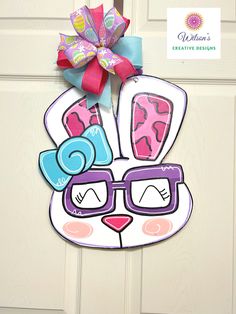 a door hanger that has a bunny wearing sunglasses and a bow on it's head