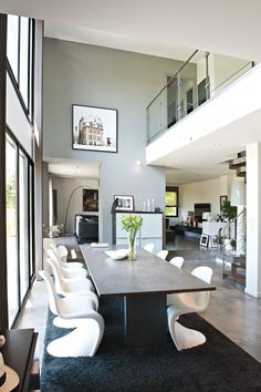 a dining room table with white chairs in front of a large open floor plan area