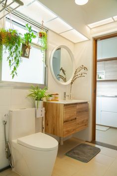 a bathroom with a sink, mirror and plants on the window sill in it