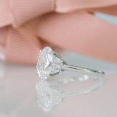 a diamond ring sitting on top of a table next to a pink satin bow tie