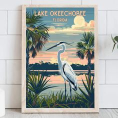 a white bird standing on top of a wooden shelf next to a wall mounted poster