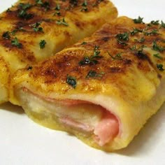 two pieces of ham and cheese stuffed with herbs on a white plate, ready to be eaten