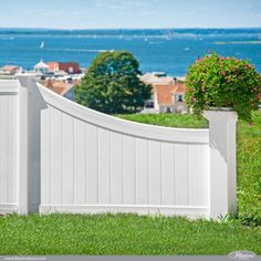 a white fence with flowers on the top and water in the background