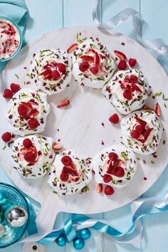 a white plate topped with cupcakes covered in whipped cream and strawberries on top