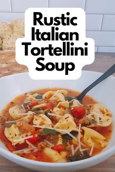 a white bowl filled with tortellini soup on top of a wooden table next to bread