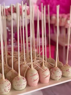 cake pops with white and pink sprinkles are arranged on a table in front of other dessert items