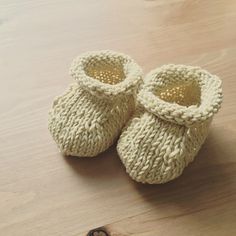 a pair of knitted baby shoes sitting on top of a wooden floor next to a key