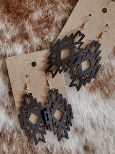 two pairs of wooden earrings sitting on top of a fur covered floor next to each other