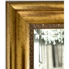 a gold framed mirror with a chandelier in the background