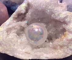 a crystal ball sitting on top of a rock next to other rocks and stones with iridescent colors