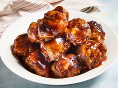 a white bowl filled with fried meat covered in bbq sauce on top of a table