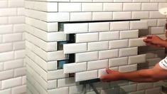 a man that is standing in front of a white wall with some tiles on it