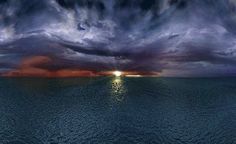 the sun is setting over the ocean with dark clouds