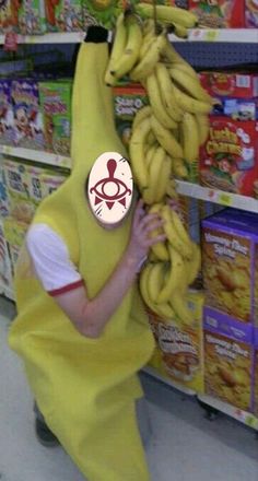 a man in a banana suit holding up a bunch of bananas to his face while standing next to a store shelf