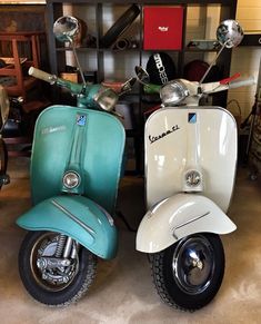 two mopeds parked next to each other in a room with shelves and chairs