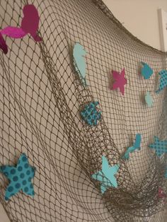 a net with blue and pink butterflies hanging from it's sides on the wall