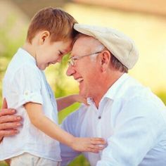 an older man holding a young boy who is wearing a white shirt and tan hat