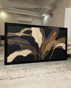 a black and gold framed art piece sitting on top of a white carpeted floor