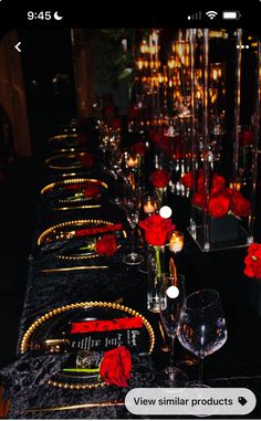 the table is set with candles and red roses in vases, plates and silverware