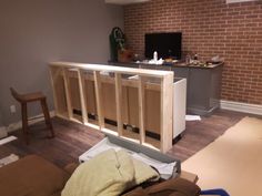 an unfinished kitchen cabinet in the middle of a living room with hard wood flooring