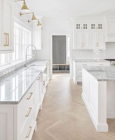 a large kitchen with white cabinets and marble counter tops