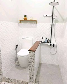 a white toilet sitting in a bathroom next to a walk in shower and tiled walls