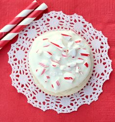 a cake with white frosting and candy canes on a doily