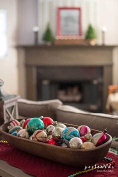 a bowl filled with ornaments sitting on top of a table next to a fire place