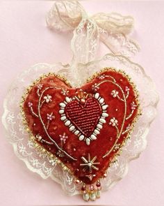 a red heart shaped ornament on a lace doily