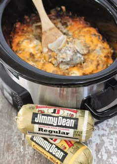 an open crock pot filled with food next to some mustard and ketchup