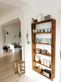 a wooden shelf filled with dishes on top of a hard wood floor