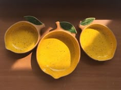 three yellow ceramic bowls with green leaves on them