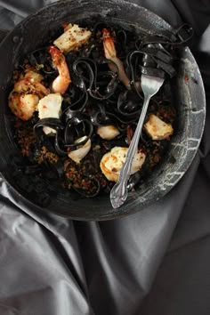 a bowl filled with pasta and shrimp on top of a bed