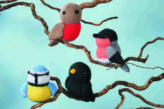 three knitted birds sitting on top of a tree branch next to another bird perched on the branch