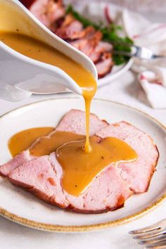 a plate with ham and gravy being poured onto it