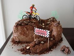 there is a cake that has a dirt bike on it and a sign in the middle