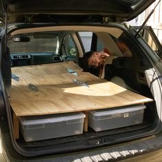 a man sitting in the back of a car with two large wooden boards on it's trunk