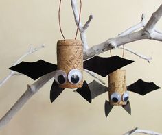 two bats hanging from the branches of a tree with eyes and noses painted on them