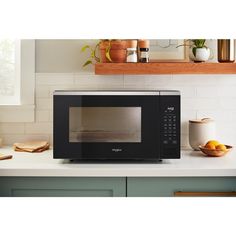 a black microwave oven sitting on top of a counter next to a potted plant