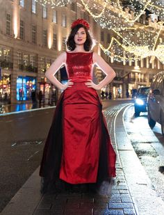 a woman in a red dress standing on the street